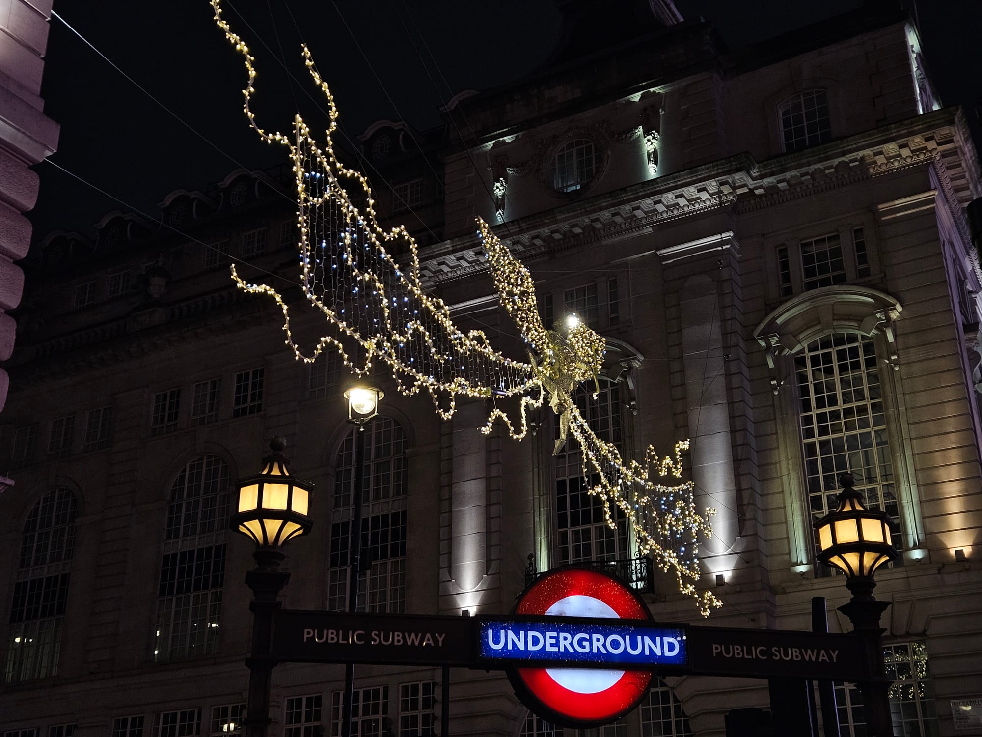 Photo of an undergound sign with Christmas decoration in the background